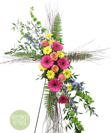 Unified Birch Cross includes gorgeous bells of Ireland, delphinium, gerbera daisies, roses, and daisy poms with Italian ruscus, fern, and birch.