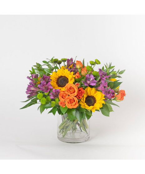 Our Shoal Creek floral arrangement, a vibrant mix of fresh sunflowers, purple alstroemeria, and orange spray roses accented with cheerful green button poms. 