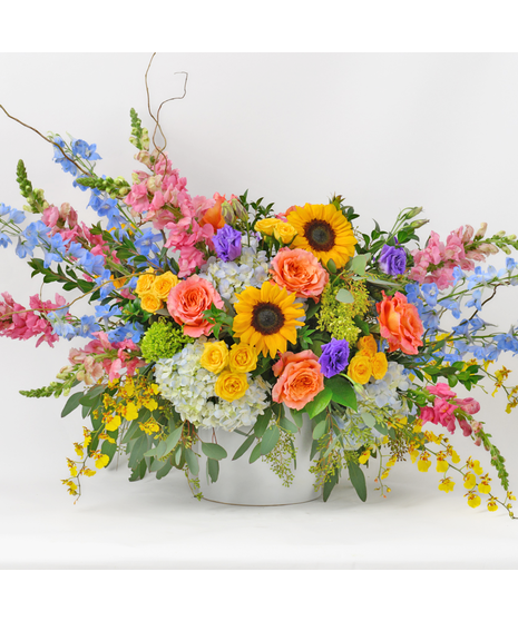 Arrangement with sunflowers, hot pink spray roses, freespirit roses, ,large blue  hydrangeas, Delphinium, and alstroemeria in a large luxury container